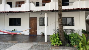 A two-story building with a tiled roof, a hammock, and potted plants.