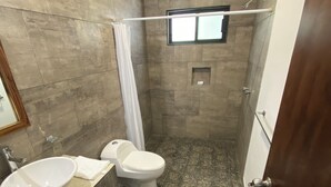 A bathroom with a large sink, toilet, and shower area.