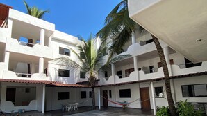 A courtyard with tiled flooring, a hammock, and potted plants.