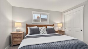 Une chambre à coucher avec un grand lit, deux tables de chevet, une fenêtre et une porte.