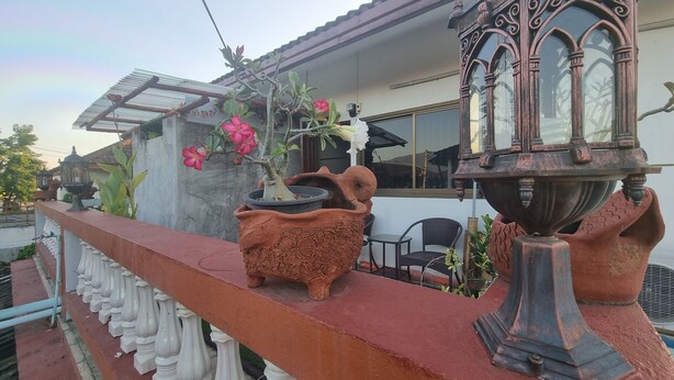 Een balkon met een bloempot, een decoratieve vaas en een stoel.
