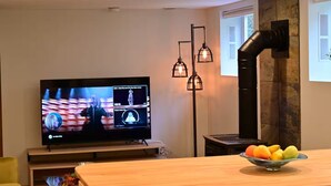 Een moderne woonkamer met een flatscreen-tv, een houten salontafel met fruit en een stenen openhaard.