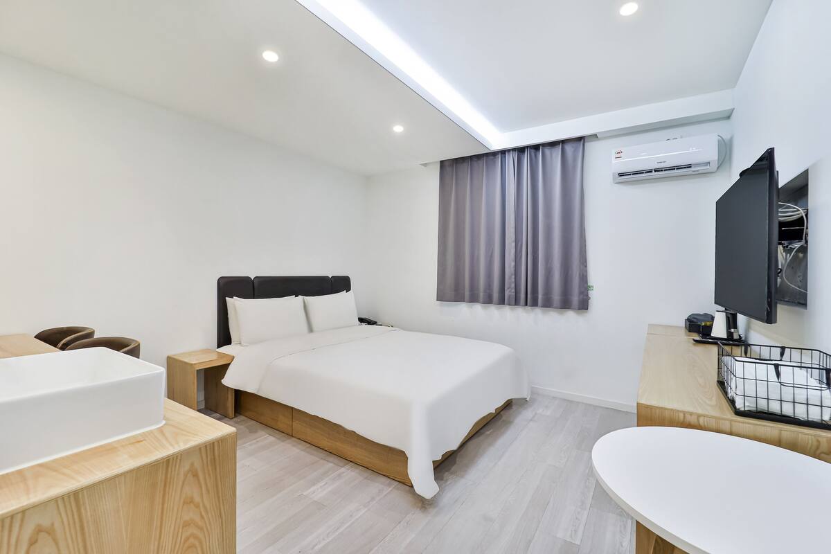 A modern hotel room with a bed, bedside table, and a built-in TV.