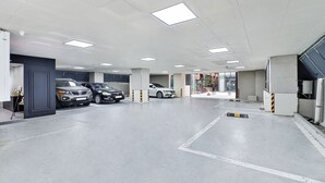A parking garage with multiple cars parked, concrete pillars, and overhead lighting. - Sloth Hotel Busan Seomyeon (Busan)