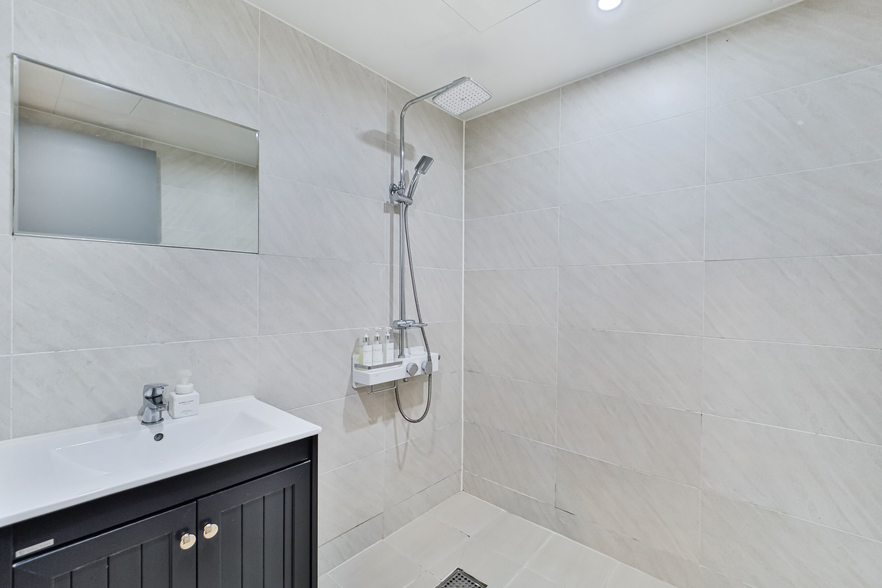A modern bathroom with a shower, a sink, and a mirror.