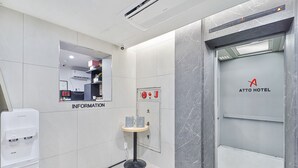 A hotel lobby with a marble wall, an information desk, a water dispenser, and an elevator with the hotel logo. - Sloth Hotel Busan Seomyeon (Busan)
