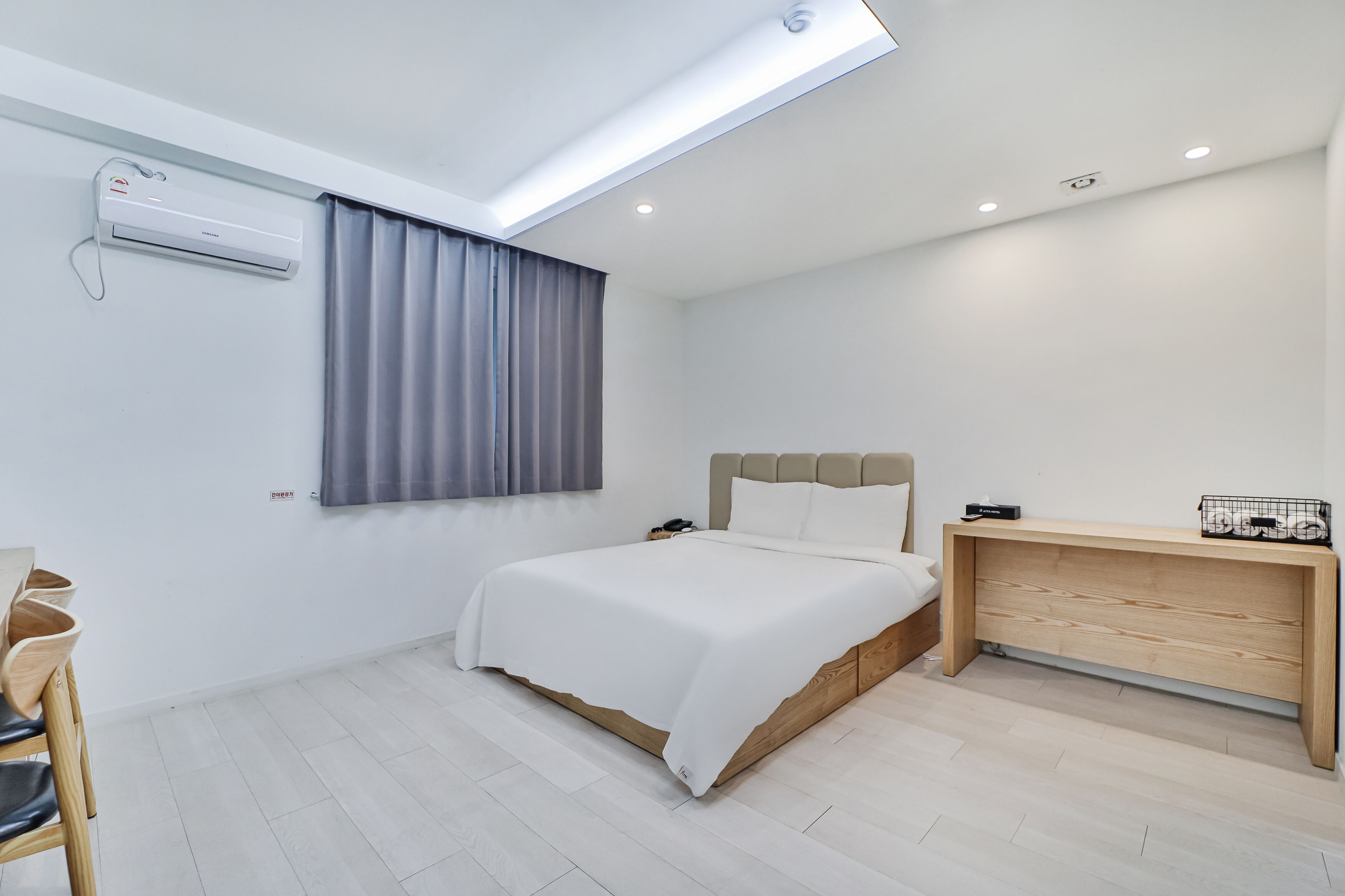 A modern bedroom with a skylight, a bed, a bedside table, and a desk.