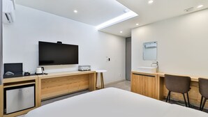 A modern hotel room with a bed, a desk with a computer, a television, a small refrigerator, a sink, and a mirror. - Sloth Hotel Busan Seomyeon (Busan)
