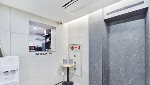 A modern elevator with a marble finish, a small information kiosk, and a hand sanitizer dispenser. - Sloth Hotel Busan Seomyeon (Busan)