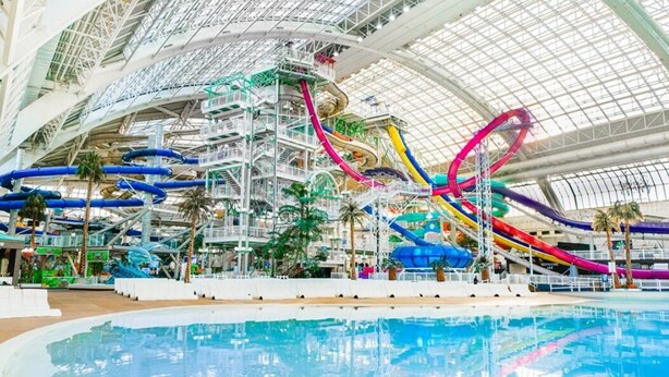 Een overdekt waterpark met meerdere glijbanen en een groot zwembad.