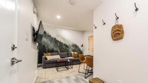 Een moderne woonkamer met een grijze bank, een salontafel, en een eethoek met een kleine tafel en stoelen.