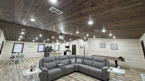 Una habitación amplia con techo de madera, un sofá seccional gris y una mesita con un adorno.