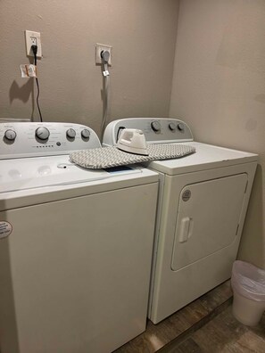 A laundry area with two washing machines and a dryer, connected to a power outlet. - Houston Family Getaway | Parking & WiFi Included! (Houston)
