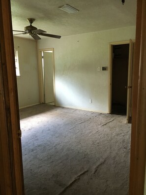 A room with a ceiling fan, a door leading to another room, and a carpeted floor. - FIFA Friendly - Large Groups Allowed (Houston)