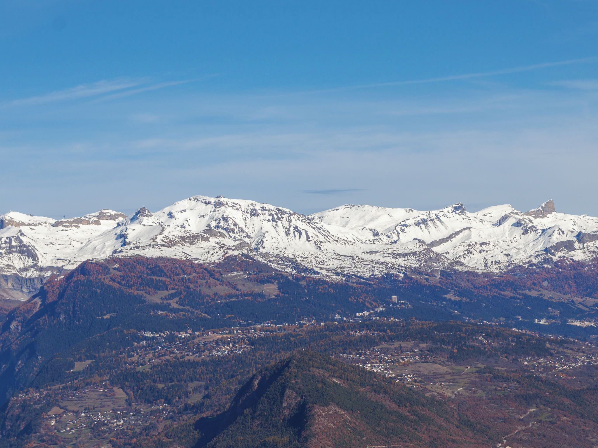 A mountainous landscape with snow-capped peaks and a valley with scattered buildings.