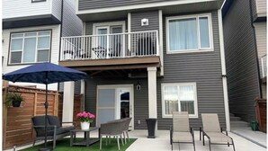 A two-story townhouse with a balcony, outdoor seating area, and a small garden. - Newly Built Guesthouse Suite (Calgary)