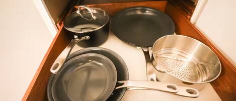 A drawer containing a frying pan, a pot, a pan, and a colander.