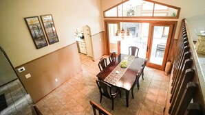 A dining area with a long table, chairs, and a kitchen in the background.
