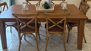 Een eettafel met vier houten stoelen, een wereldkaart aan de muur en een kleine plant op de tafel.