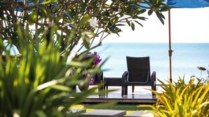 Ein Stuhlgarnitur mit Tisch steht auf einer Terrasse mit Blick aufs Meer.