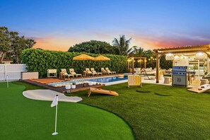 A backyard with a swimming pool, lounge chairs, a barbecue area, and a well-maintained lawn. - Wellness Retreat at WPB - HotTub | Sauna | ColdPlunge | Golf (West Palm Beach)