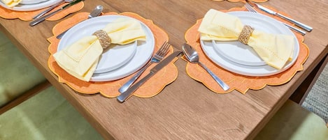 Una mesa puesta con platos, cubiertos y servilletas.