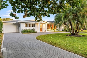 A modern two-story house with a paved driveway leading to a garage and a covered patio area.