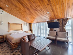 A room with a wooden ceiling, a bed with pillows, a sofa, a TV, and a window with curtains. - Virgo Villa Que Hoi An (Hoi An)
