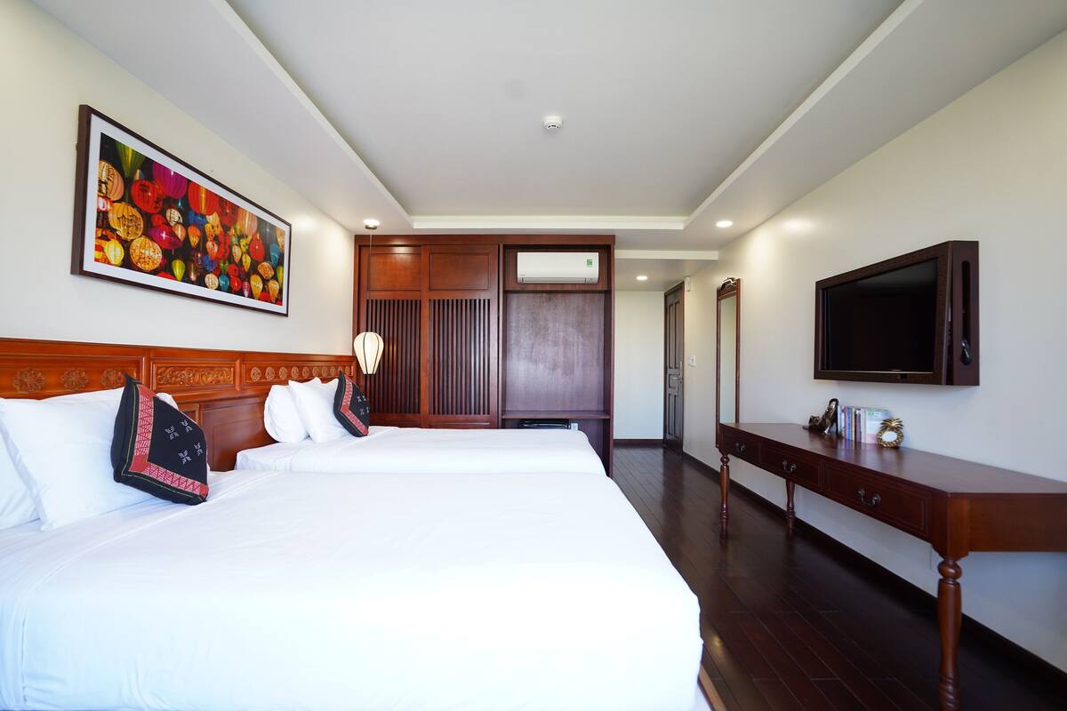 Een hotelkamer met een groot bed, een houten hoofdbord, een flatscreen televisie, een houten dressoir en een schilderij aan de muur.