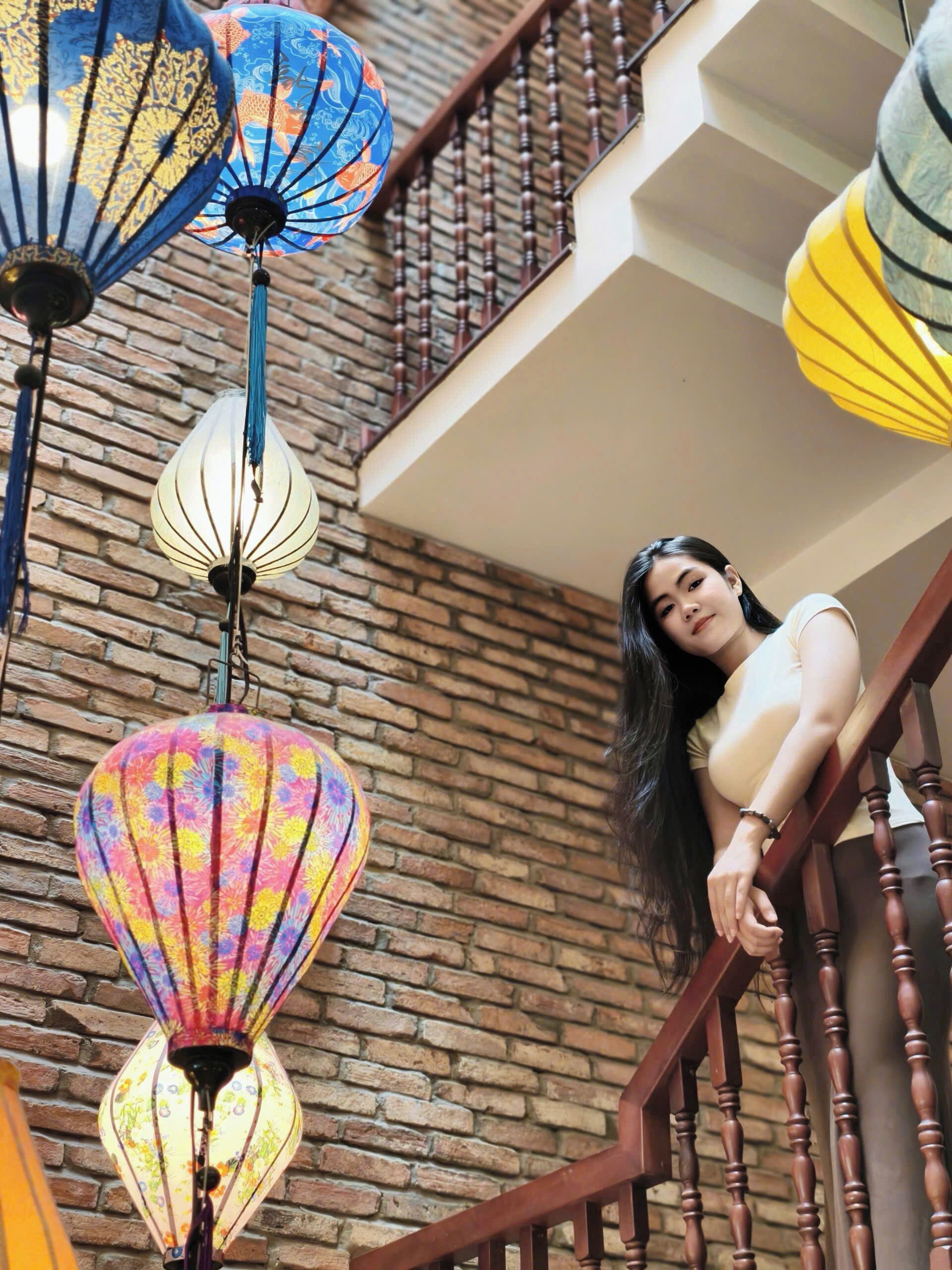 A staircase with a brick wall background and hanging lanterns.
