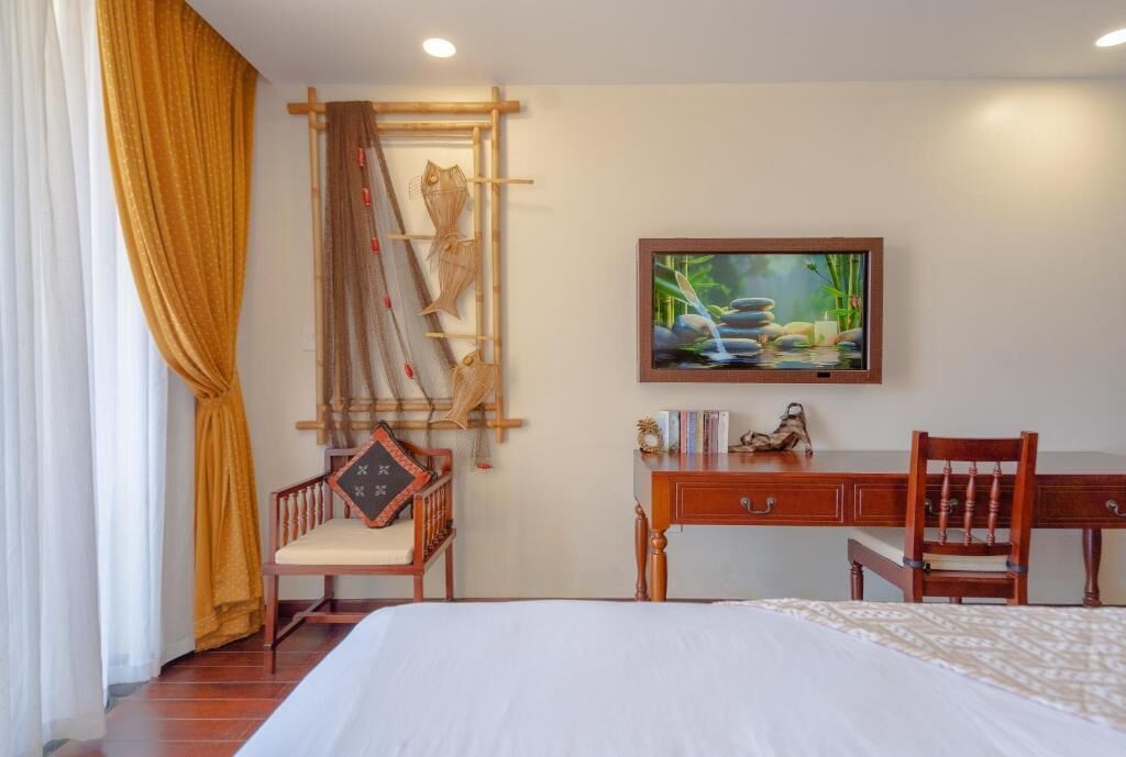 Una habitación de hotel con cama, escritorio, silla, un cuadro y una escalera de bambú para peces.