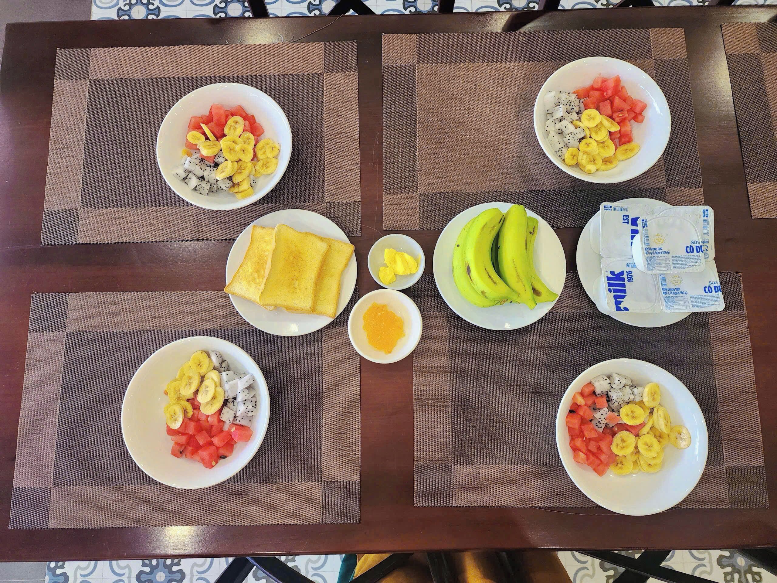 A table with breakfast items including toast, bananas, eggs, and milk cartons.