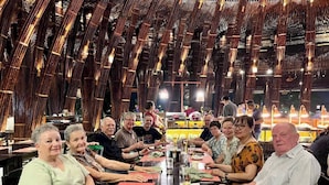 A group of people seated around a long table in a restaurant with a modern, wooden interior and hanging lights. - Virgo Villa Que Hoi An (Hoi An)