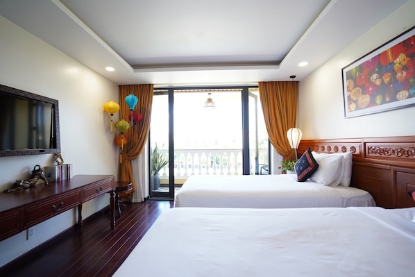 A hotel room with a large bed, a TV, a desk, and a balcony with curtains. - Virgo Villa Que Hoi An (Hoi An)