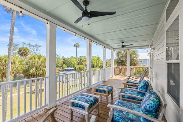 A covered porch with wooden furniture and a view of the outdoors. - Riverbend Landing - Steinhatchee (Steinhatchee)