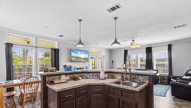 A modern kitchen with dark wood cabinets, a granite countertop, and a built-in sink. - Riverbend Landing - Steinhatchee (Steinhatchee)