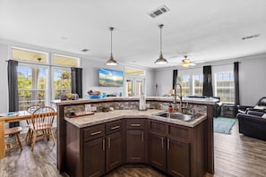 A modern kitchen with dark wood cabinets, a granite countertop, and a built-in sink. - Riverbend Landing - Steinhatchee (Steinhatchee)