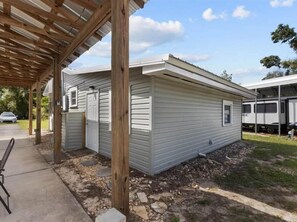 Une maison mobile de plain-pied dotée d’un porche couvert, d’un petit garage attenant et d’une allée pavée.