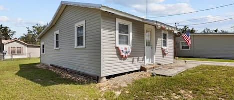 A single-story mobile home with a gabled roof, a front porch, and a small front yard.