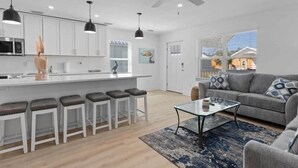 A modern kitchen with white cabinets, a central island with stools, and a ceiling fan. - The Pelican Pad - Steinhatchee (Steinhatchee)
