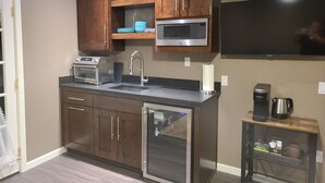 Una cucina moderna con mobili in legno, un forno a microonde in acciaio inox, una macchina da caffè e una TV integrata.