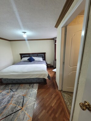 A bedroom with a bed, a small round table, a door, and a patterned rug. - Spacious apartment in downtown Quito, perfect for your getaway (Quito)
