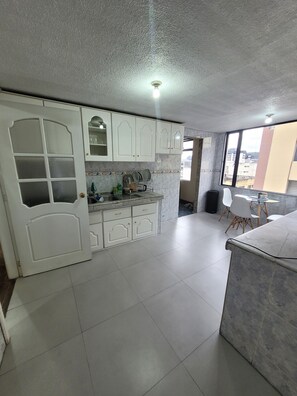 A kitchen with white cabinets, a tiled floor, and a window with a view of buildings. - Spacious apartment in downtown Quito, perfect for your getaway (Quito)
