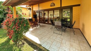 An outdoor patio with a brick floor, wooden furniture, and a grill. - House in the wonderful Pauba Condominium, a small village. (São Sebastião)