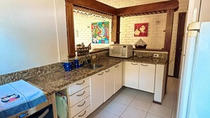 A kitchen with white cabinets, a microwave, a stove, and a refrigerator. - House in the wonderful Pauba Condominium, a small village. (São Sebastião)