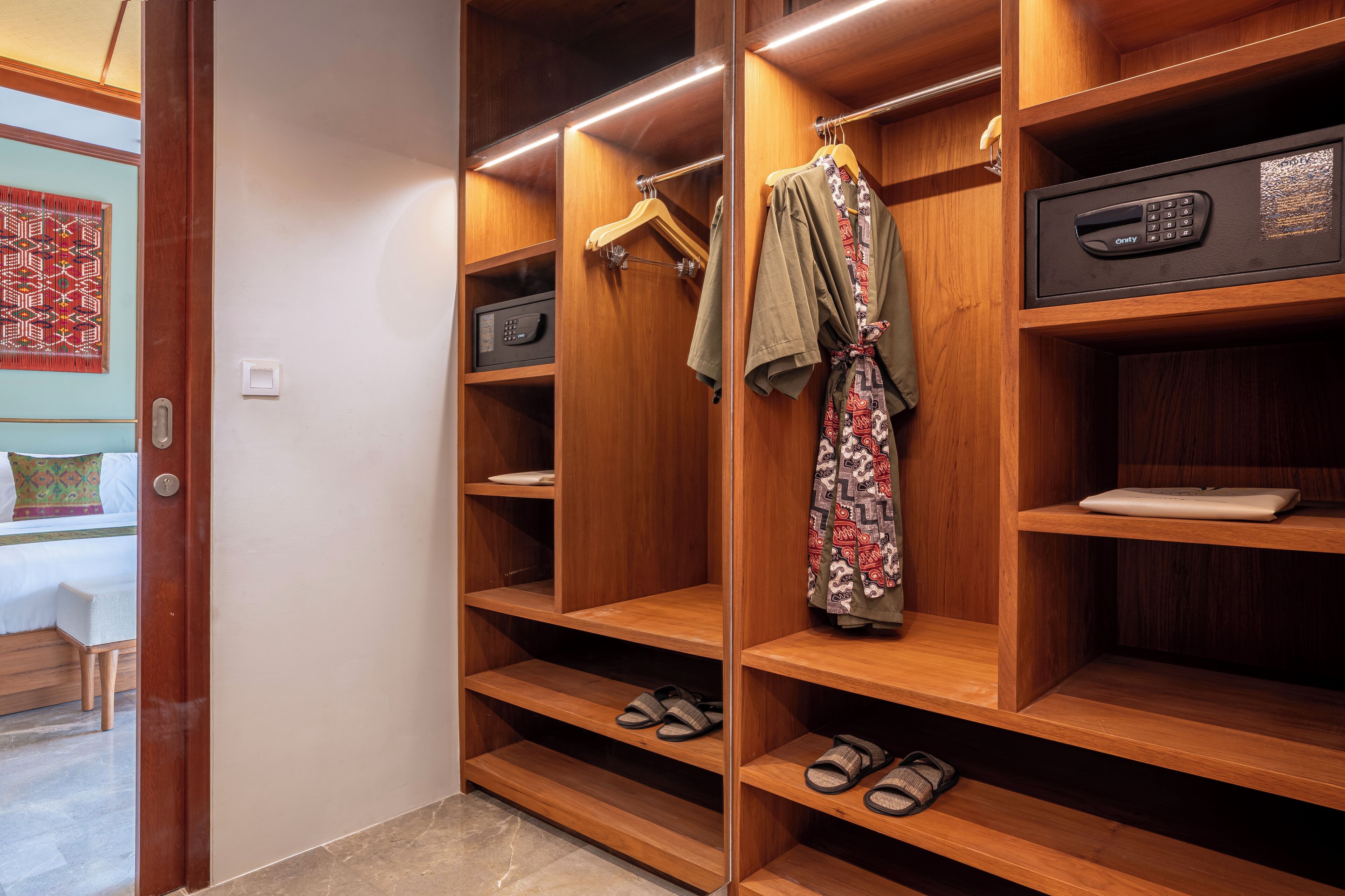 A wooden closet with shelves, a hanging rack, and a safe.