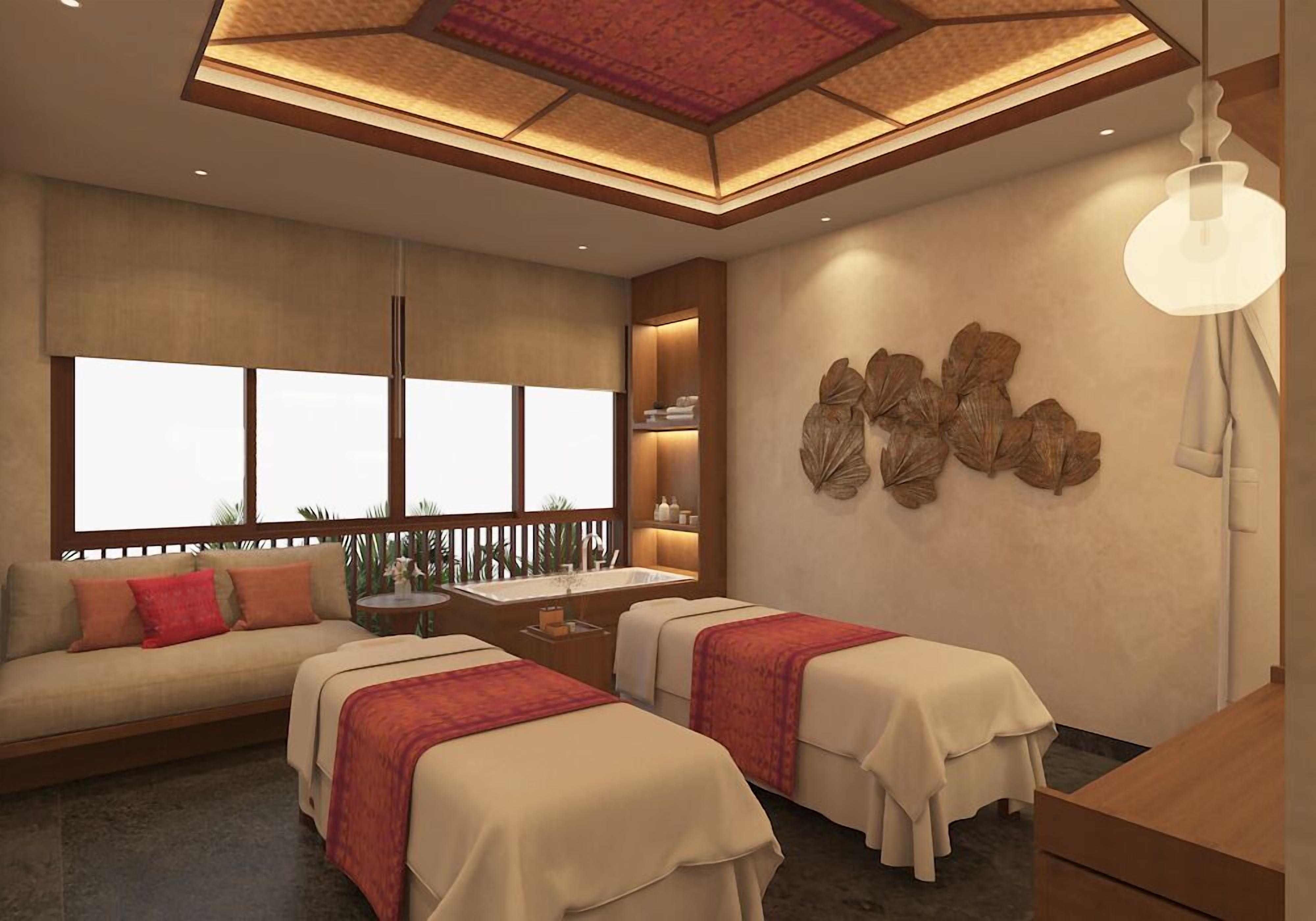 A hotel room with a sofa, two beds, a small table, a sink, and a decorative wall piece.