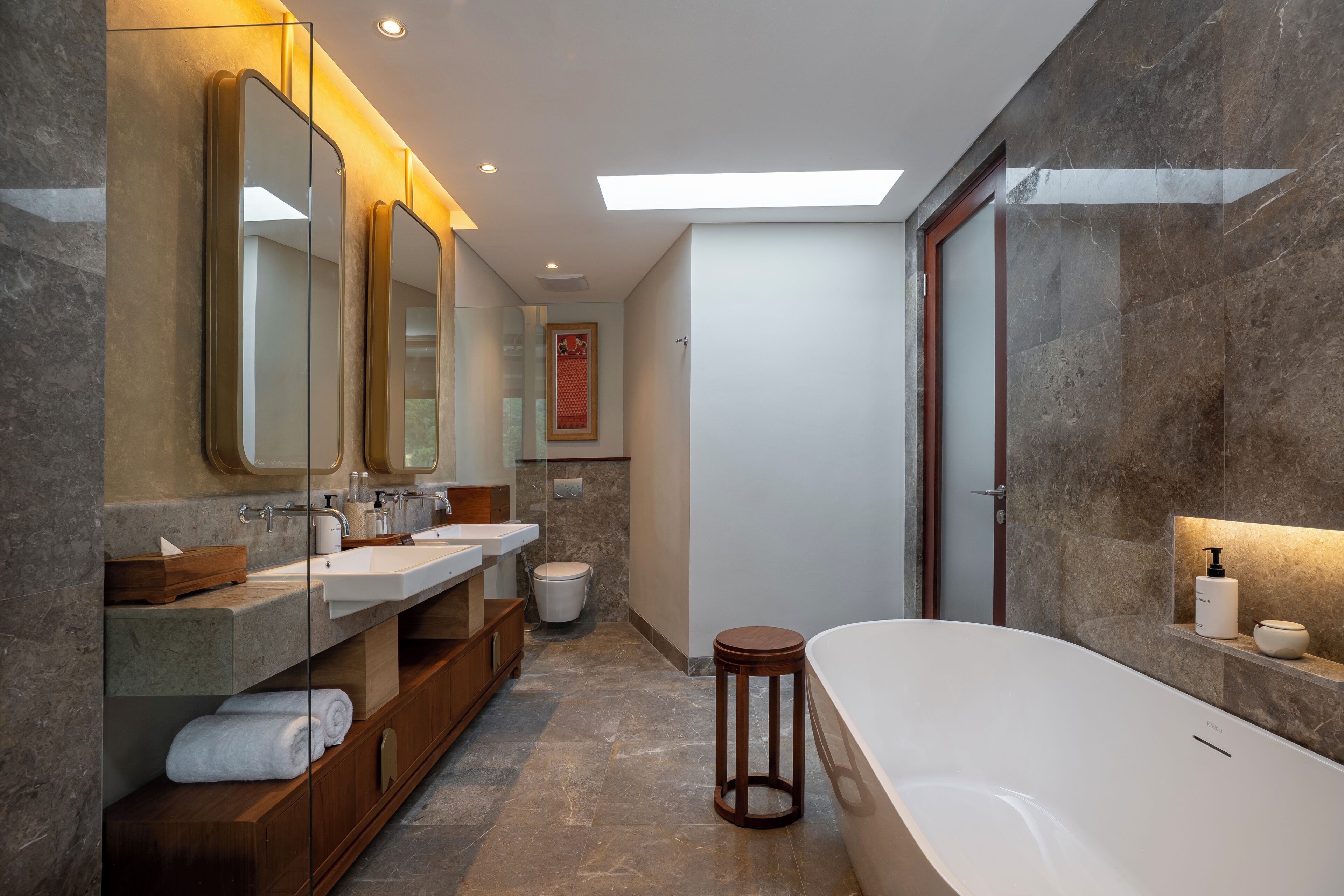Un baño moderno con una bañera grande, dos lavamanos y un mueble de tocador con espejo.
