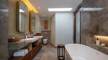 Un baño moderno con una bañera grande, dos lavamanos y un mueble de tocador con espejo.