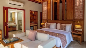 Una habitación de hotel con una cama grande, un sofá, una mesita de noche y un espejo.